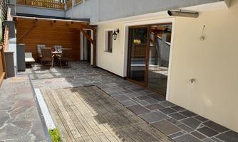 A cozy terrace with a stone and wooden surface. There is a dining table and chairs for outdoor relaxation.