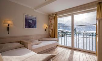 A cozy room with two beds and large windows that overlook a snow-covered landscape. The warm colors and wooden design create an inviting atmosphere.
