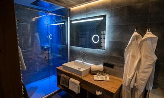 A modern bathroom with a walk-in shower and an elegant sink. Soft bathrobes hang ready while gentle lighting creates a relaxing atmosphere.