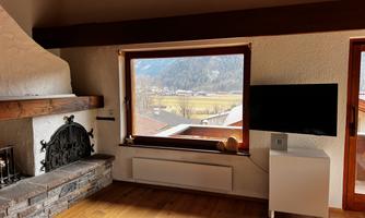 View from the couch in the living room of the television, fireplace, and mountains