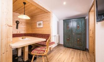 A cozy dining area with wood panels and a large farmhouse cupboard. The room has a warm atmosphere and is well-lit.
