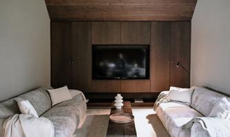 A modern living room with two bright sofas and a TV on the wall. A stylish table with decorative elements complements the decor.