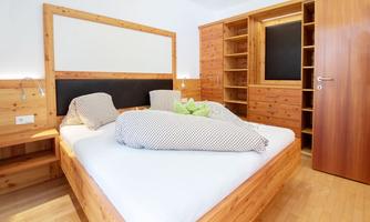 A cozy bedroom with a large wooden bed and modern furniture. The warm wooden tones create an inviting atmosphere.