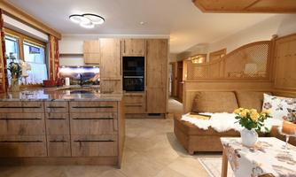 A modern wooden kitchen with a cozy living area. The room is bright and inviting, perfect for relaxing moments.