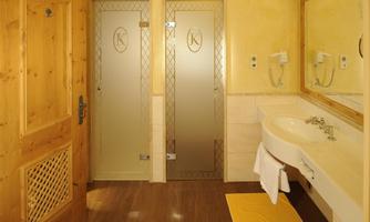 A modern bathroom with wooden cladding and a light color scheme. It features two glass doors and a sink with a mirror.