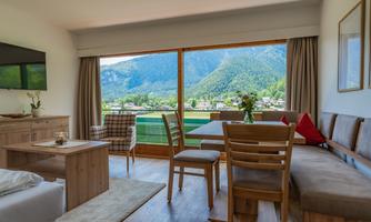 A cozy living space with a large window that offers a view of the mountains and the landscape. The decor is modern and inviting.