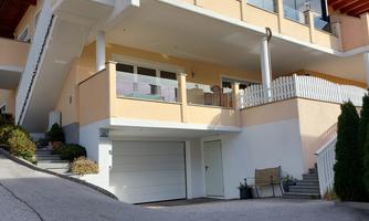 A modern house with several floors and a large balcony. The facade is bright and the surroundings are well maintained.