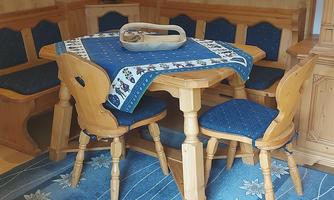 A cozy room with a wooden table and two chairs. The blue carpet with floral patterns completes the warm atmosphere.