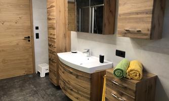 A modern bathroom with wooden details and a curved sink. Fresh towels in yellow and green are ready.
