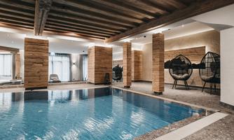 A modern interior with a pool and wooden columns. Cozy wicker seating creates a relaxed atmosphere.