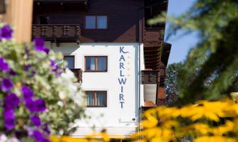A charming building named "Karl Wirt" is visible in the background. Surrounded by colorful flowers, it creates an inviting atmosphere.