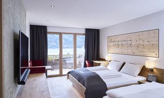 Modern hotel room with large windows and a view of nature. It is cozily furnished with a double bed and a television.