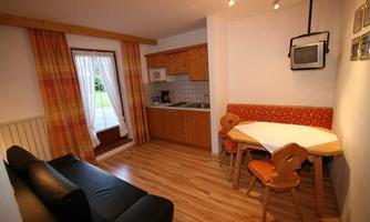 A cozy holiday apartment with a kitchenette and a dining table. The living room is bright and features a large window with access to the terrace.