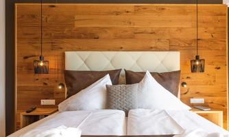 A modern bedroom with a wood panel and a cozy, inviting atmosphere. The beds are decorated with white blankets and pillows.