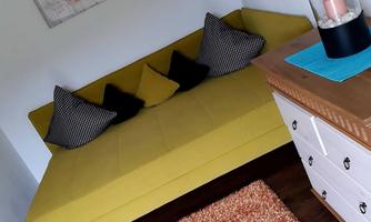 A modern room with a yellow sofa and decorative cushions. Next to the sofa is a stylish table with a candle and a carpet.