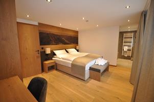 A modern bedroom with a double bed and wooden interior. There is soft lighting and a pleasant atmosphere.