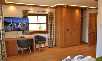 A cozy room with wooden details and warm light. A television and a large wardrobe are also available.