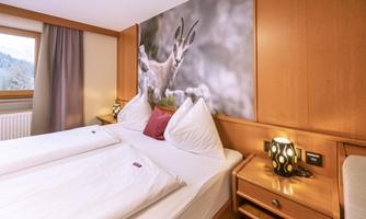 A cozy room with two beds and wooden decor. On the wall hangs a picture of a deer in nature.