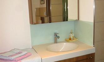 A modern bathroom with a sink and a large mirror. It includes towels on the left side and a bright, friendly color scheme.