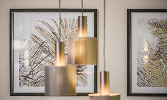 Modern interior design with an elegant ceiling light and two framed images of palm leaves. The soft colors create a harmonious atmosphere.