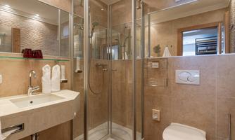 A modern bathroom with a glass shower and a sink. The walls are in neutral colors and there are fresh towels.