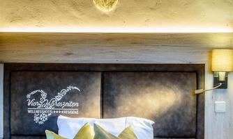 A cozy bedroom with a bed and decorative pillows. A deer head hangs on the wall, and soft lighting creates a pleasant atmosphere.