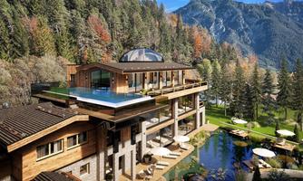 A modern villa in the mountains with a rooftop pool. Surrounded by trees and a picturesque landscape.