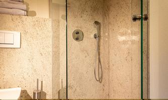 A modern shower with a glass partition and an elegant stone wall. Towels are included.