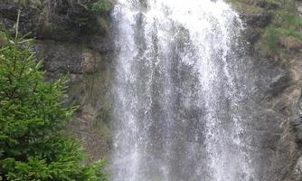 A beautiful waterfall cascading over rocks, surrounded by green trees. Nature is lush and peaceful.