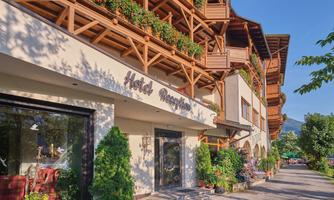 A charming hotel with a wooden porch and blooming plants. The facade radiates hospitality.