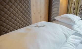 A cozy bed with white pillows and a tufted headboard. The surroundings radiate a warm and inviting atmosphere.