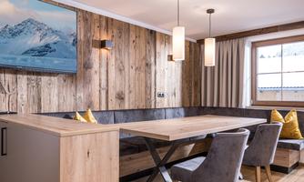 A modern dining room with wooden walls and a large table. Cozy chairs and a piece of art on the wall create an inviting atmosphere.