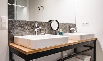 A modern bathroom with a double sink and large mirror. Fresh towels are neatly arranged, and the space has an elegant, minimalist design.