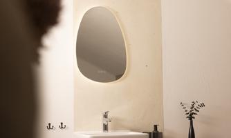 A modern bathroom with a sink and an oval mirror. In the background, decorative elements can be seen that enhance the appeal of the space.
