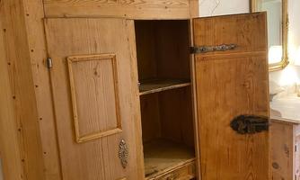 A rustic wooden cabinet with open doors that provides space for items. On top of the cabinet sits a decorative bowl.