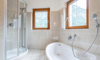 A modern bathroom with a shower and a bathtub. Large windows let in plenty of light.