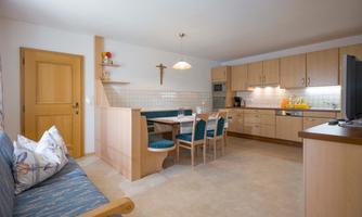 A bright, modern kitchen with a dining area and wooden cabinets. The room is tastefully decorated and offers a pleasant atmosphere.