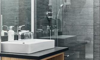 A modern bathroom with an elegant sink setup on a wooden console. The walls are kept in a simple gray, and the shower area is clearly separated.