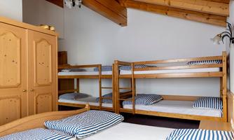 A simple room with bunk beds and mattresses. The walls are light, and the ceiling has visible wooden beams.
