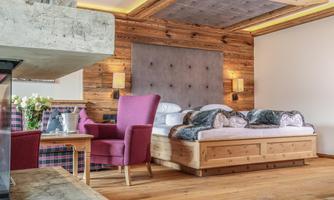 A cozy bedroom with warm wood elements and a large window. A comfortable bed and cozy furniture invite you to relax.