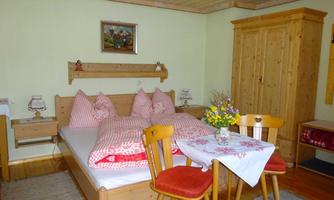 A cozy room with a double bed and wooden furniture. A table with a bouquet creates an inviting atmosphere.