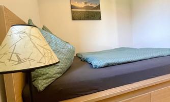 A cozy bedroom with a double bed and a modern lamp. A picture of a landscape hangs on the wall.