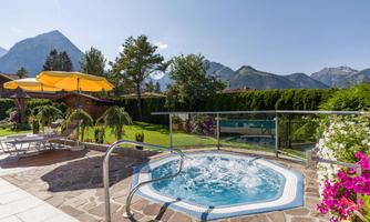 A whirlpool in a beautiful garden with a view of the mountains. The garden is adorned with colorful flowers and sun loungers.