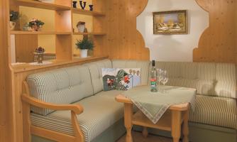 A cozy seating area with a light wood paneling and striped cushions. On the table are a bottle of water and glasses.