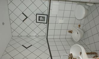 A modern restroom with white tiles and golden fixtures. There is a sink, a bidet, and a toilet.