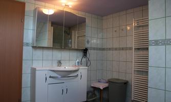 A modern bathroom with bright tiles and a sink. A hairdryer and towels are hanging on the wall.