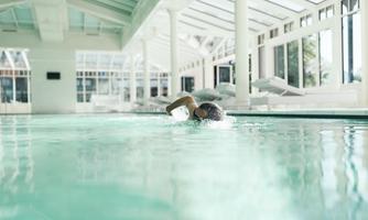 A swimmer is in a bright indoor pool. The atmosphere is calm and relaxing.