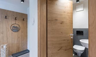 A modern bathroom with a wooden door and stylish accessories. The walls are bright, and the sanitary facilities are well arranged.