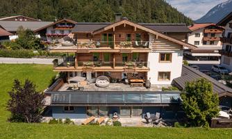A charming house with wooden cladding and several balconies. Surrounded by green meadows and mountains, it offers a beautiful view.