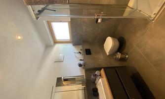 A modern bathroom with a shower, a sink, and a modern toilet. The walls are bright and the decor is minimalist.